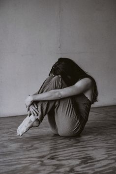 a black and white photo of a woman sitting on the floor with her hands behind her head