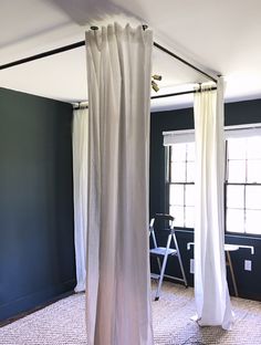 an empty room with white curtains hanging from the ceiling