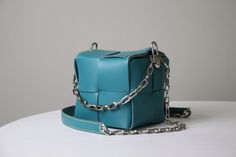 "Enjoy your special time wiht our DIY kit together with easy-follow online tutorial. This Cube bag, an elegant leather bag in a dice shape. It is create in a good size, decorated with handle chain, and shoulder chain with supportive leather pad.  You can finish your daily look with this cute bag which is created by yourself! [ 𝙁𝙚𝙖𝙩𝙪𝙧𝙚 & 𝘿𝙚𝙨𝙞𝙜𝙣 ] - A Nappa leather handbag with a shoulder chain. - Secured your stuffs by magnetic cover. - Handcrafts with premium materials by artist. - Suitable for everyday use. - Large capacity, fit for phone upto pro max. [ 𝙋𝙖𝙘𝙠𝙖𝙜𝙚 𝙞𝙣𝙘𝙡𝙪𝙙𝙚𝙙 ] DIY Kit \"Cube bag\" - A set of leather pieces with punched holes (your chosen color) - A bag chain, and handle. - Thread (similar color to the leather color) - Edge Paint (similar color to t Designer Leather Box Bag As A Gift, Designer Bucket Box Bag As Gift, Modern Bucket Bag As Gift, Modern Bucket Bag For Gift, Modern Bucket Bag For Gifts, Modern Bucket Shoulder Bag For Gift, Leather Bucket Box Bag As A Gift, Modern Rectangular Bags As Gifts, Modern Rectangular Bags For Gifts