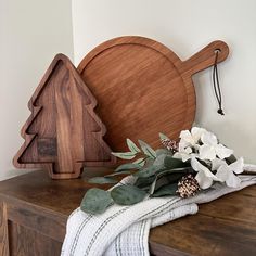 a wooden cutting board sitting on top of a table next to flowers and a towel