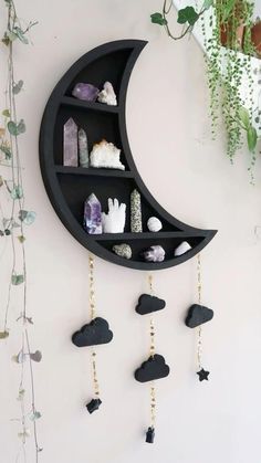 a crescent shaped shelf with rocks hanging from it's sides and a moon on the wall