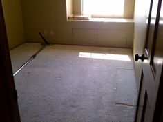 an empty room with a window, carpet and door handle on the floor in front of it