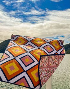 a colorful kite sitting on top of a wooden post near the water's edge