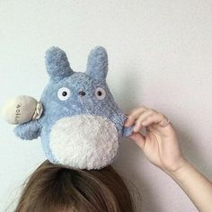 a woman holding up a stuffed animal on top of her head to the side with eyes