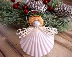 a white angel ornament sitting on top of a wooden table next to pine cones