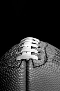 a close up of a football on a black background with white laces and the letter e