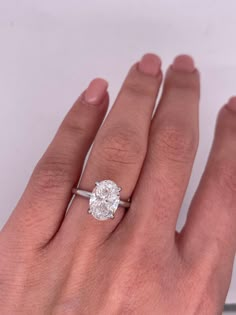 a woman's hand with a diamond ring on top of her finger and the other hand holding an engagement ring