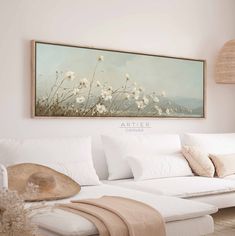 a living room with white furniture and a painting on the wall above it's couch