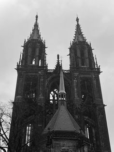 an old church with two steeples and a clock on the front tower is shown in black and white