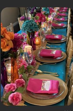 the table is set with pink and gold plates, silverware, and purple napkins