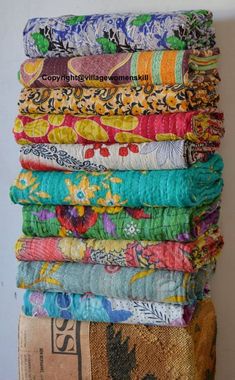 a stack of colorful cloths sitting on top of a wooden table next to a wall