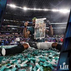 a football player sitting on the sidelines with his foot up and holding a newspaper