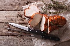 sliced pork with herbs and knife on wooden table