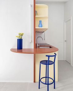 a blue chair sitting in front of a counter top next to a vase with flowers on it