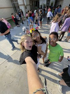 some kids are taking a selfie in front of a building while others stand around