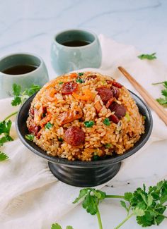 a bowl filled with rice and meat on top of a table next to chopsticks