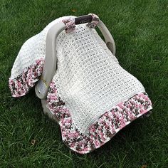 a crocheted blanket on the grass with a baby car seat attached to it