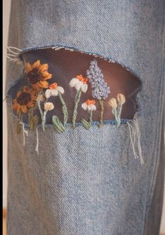 an old pair of jeans with embroidered flowers on them