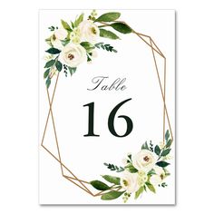 a table number with white flowers and greenery in the center on a white background