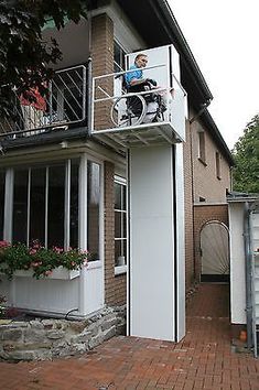 a man in a wheel chair on top of a balcony next to a brick building