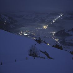 a snowy mountain with lights in the distance