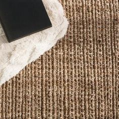 a black book on top of a brown and white rug next to a pile of blankets