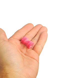 a hand holding a tiny pink object in it's palm