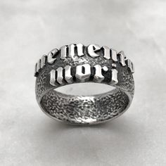 The Memento Mori Ring is not just a piece of jewelry; it is a talisman of empowerment and introspection. By wearing this ring, you carry a symbol of your own mortality, inviting reflection and inspiring a deeper appreciation for the fleeting beauty of life. It serves as a reminder to live fully, embracing the joys and challenges that come your way. DIMENSIONS Ring is 8mm wide. MATERIAL 925 Sterling Silver. Each piece is handmade to order in our Jewel Thief Brighton atelier. Memento Mori Ring, Embossed Jewelry, Phrase Meaning, Silver Skull Ring, Coin Pendant Necklace, Skull Ring, Memento Mori, Coin Pendant, Star Pendant