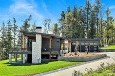 a modern house in the woods with lots of trees and grass on both sides of it