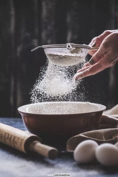 someone is sprinkling flour into a bowl