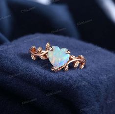 an opal heart shaped ring with leaves on it