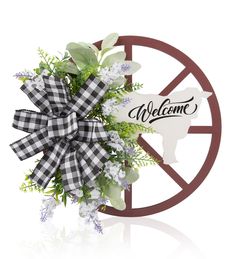 the welcome sign is decorated with flowers and greenery in front of a wagon wheel