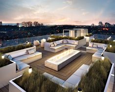 an outdoor living area with couches, tables and fire pit on the roof at night