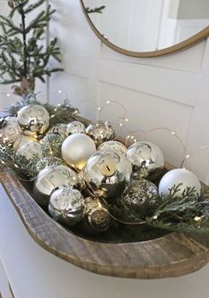 a wooden shelf filled with ornaments on top of a counter next to a mirror and christmas tree