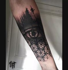 an eye tattoo on the arm with trees and mountains in the background, as well as stars