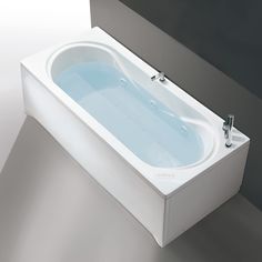 a white bath tub sitting on top of a gray floor next to a sink and mirror