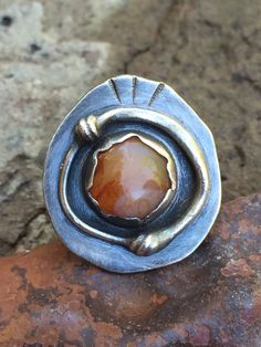 "This unique metalwork ring features a lovely polished agate pebble that was collected from the Oregon coast. The setting is made by hand from fine (.999) and Sterling (.925) silver. The silver has been oxidized and then polished to highlight certain areas of interest on the detailwork of the metal. This ring is perfect for fall and has a modern BOHO vibe. The ring in the photos has sold. Your ring will be made in the same style but expect some slight variances in texture and stone shape (they'r Artisan Untreated Open Ring Jewelry, Artisan Hand Forged Oval Ring, Unique Oval Opal Ring For Jewelry Making, Earthy Gemstone Rings For Gifts, Earthy Gemstone Rings As Gifts, Earthy Gemstone Rings For Gift, Vintage Agate Jewelry With Large Stone, Bohemian Agate Ring With Large Stone, Unique Handmade Oval Cabochon Moonstone Ring