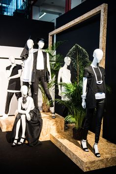 mannequins dressed in black and white sitting on wooden steps next to plants