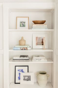 a white book shelf filled with books and pictures