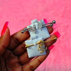 a person holding three different types of hair clips in their hand with pink and white background