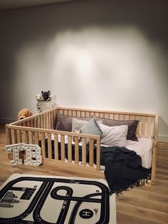 a baby crib in the corner of a room next to a rug and stuffed animals