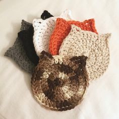 four crocheted cat purses on a white bed with one in the middle