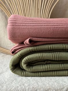 two blankets folded on top of each other in front of a wicker headboard