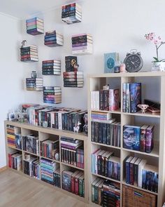 a bookshelf filled with lots of books next to a clock and wall mounted pictures