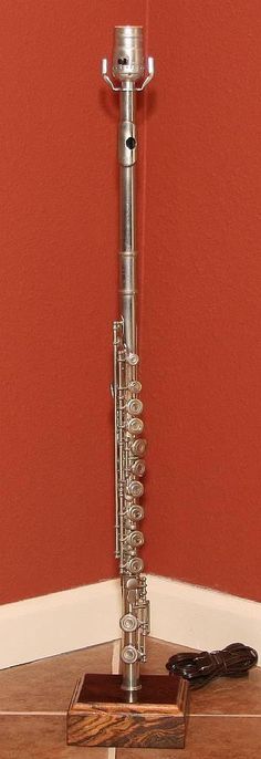 a silver pipe sitting on top of a wooden table next to a red painted wall