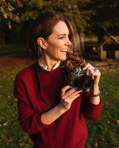 a woman in a red sweater is holding a camera