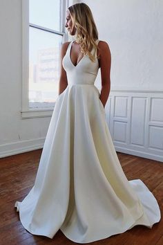 a woman in a white wedding dress standing on a wooden floor next to a window