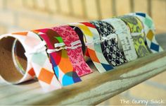 several rolls of colorful patterned paper sitting on top of a wooden bench