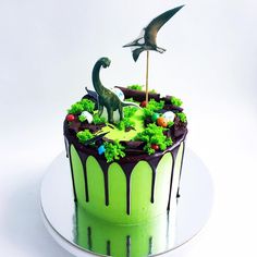 a dinosaur cake with green icing and decorations