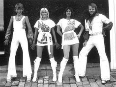 an old black and white photo of four people dressed in 70s style clothing posing for the camera